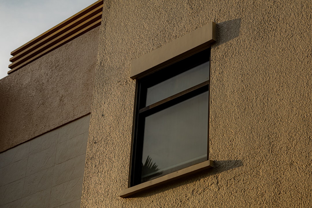 Fenêtre projetant une ombre sur un mur en stuc. Pensez films solaires bâtiment résidentiel Vaud.