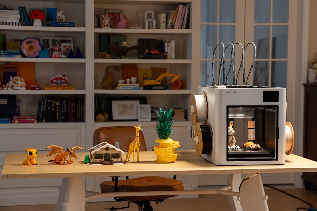 3D printer with toys and books on shelf