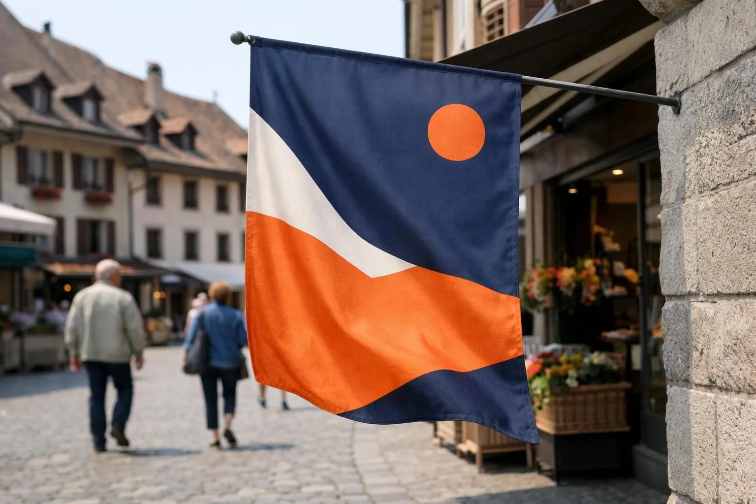 Close-up view of colorful fabric flag banners gently waving in front of a Swiss storefront with pedestrians walking on a cobblestone street in a traditional Romandy town square, bright daylight highlighting the movement and texture of the promotional flags