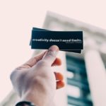 "Personne tenant une carte de visite personnalisée rapide avec un motif en noir et blanc."