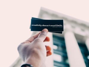 "Personne tenant une carte de visite personnalisée rapide avec un motif en noir et blanc."
