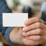 "Main tenant une carte de visite professionnelle avec un fond de bureau en bois"