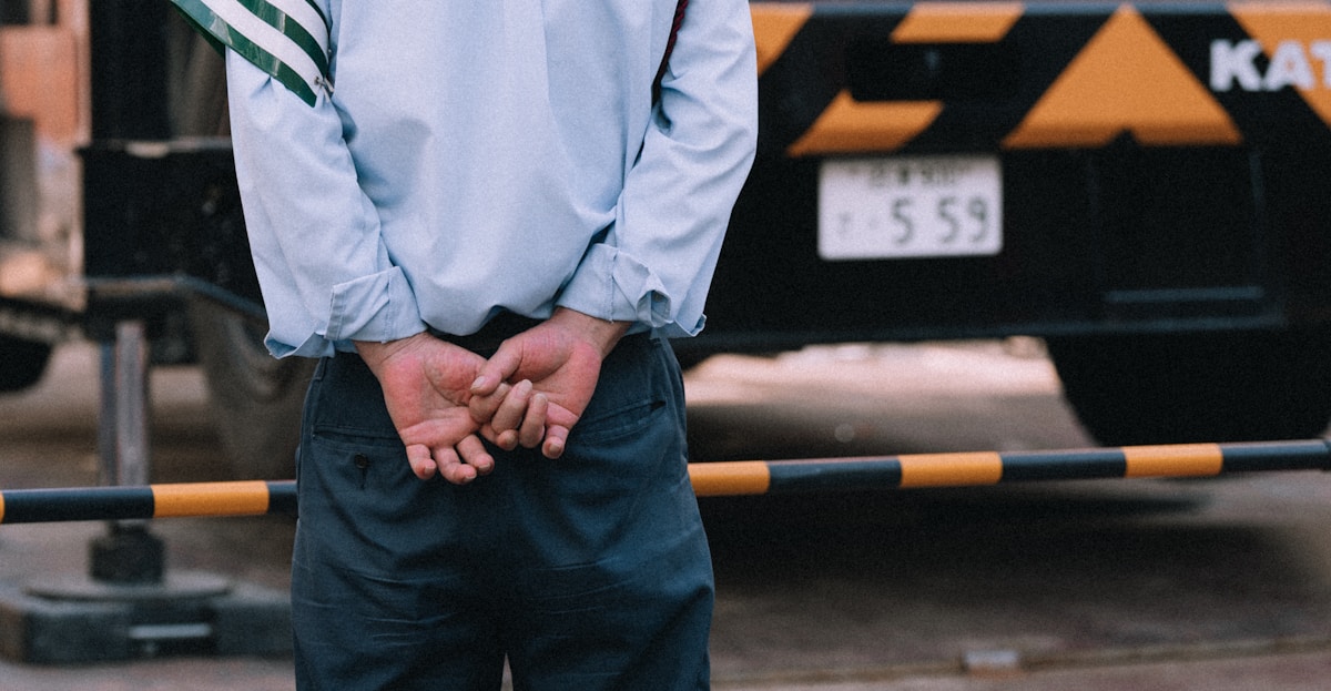 Homme en uniforme de travail, debout devant un équipement industriel.