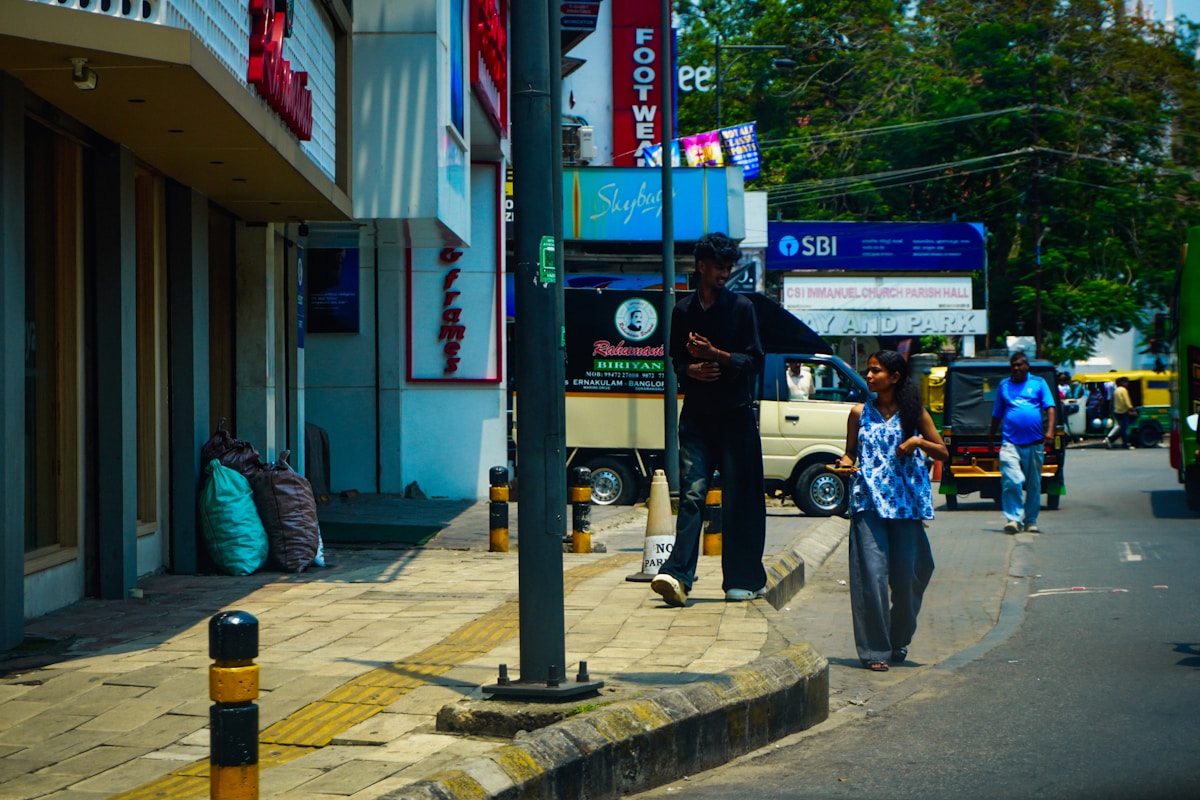 Scène de rue animée avec boutiques, passants et véhicules.