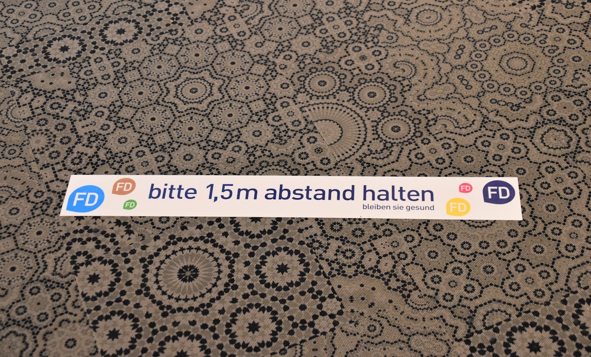 Motifs géométriques complexes sur un fond beige, avec un message en allemand.