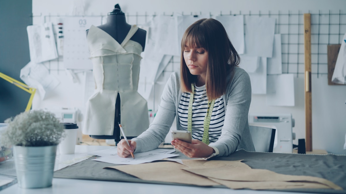 Une femme concentrée sur son travail de conception de mode dans un atelier.