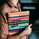 Un homme tenant un livre sur la création d'identité de marque, illustrant l'importance du branding pour les PME.