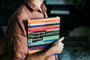 Un homme tenant un livre sur la création d'identité de marque, illustrant l'importance du branding pour les PME.