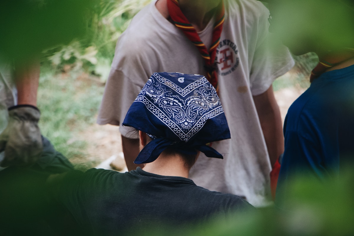 Homme portant un bandana bleu et blanc dans un environnement verdoyant.
