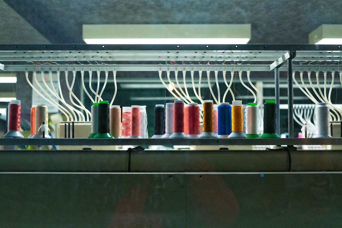 Bobines de fil multicolores sur un présentoir dans un atelier de couture.