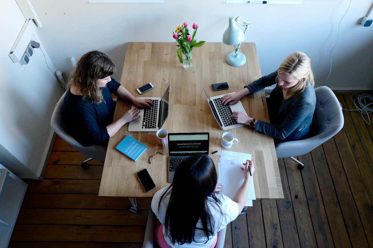 Trois personnes travaillant ensemble sur des ordinateurs portables dans un bureau.