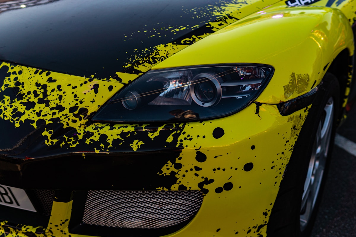 Voiture de sport jaune et noire avec des éclaboussures de peinture.