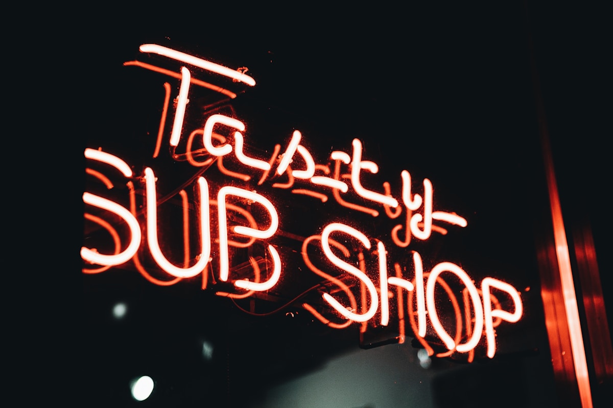 Enseigne au néon rouge avec le texte "Taupery Sub Shop".