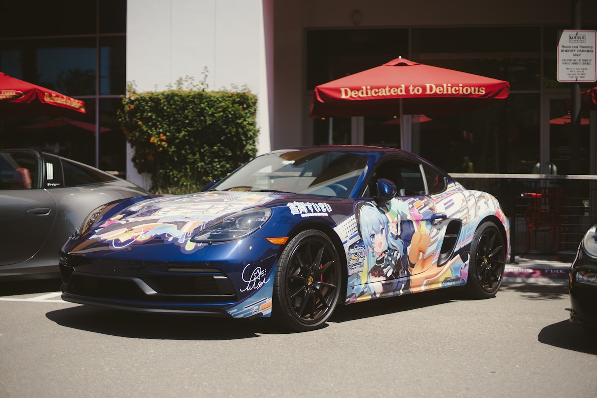 Voiture de sport bleue décorée d'illustrations anime, garée devant un restaurant.
