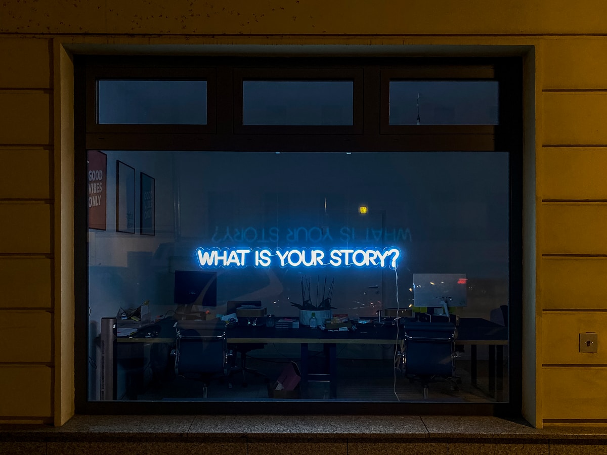 Fenêtre éclairée par une enseigne lumineuse "What is your story?"