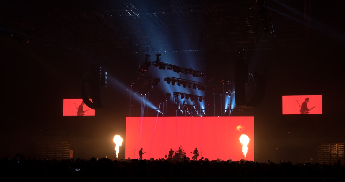 Scène de concert rock avec éclairage dramatique et effets pyrotechniques.