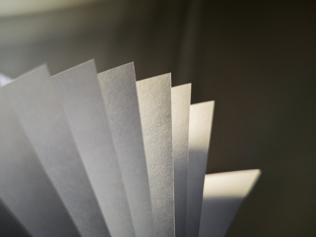 Feuilles de papier gris et blanc empilées en diagonale.