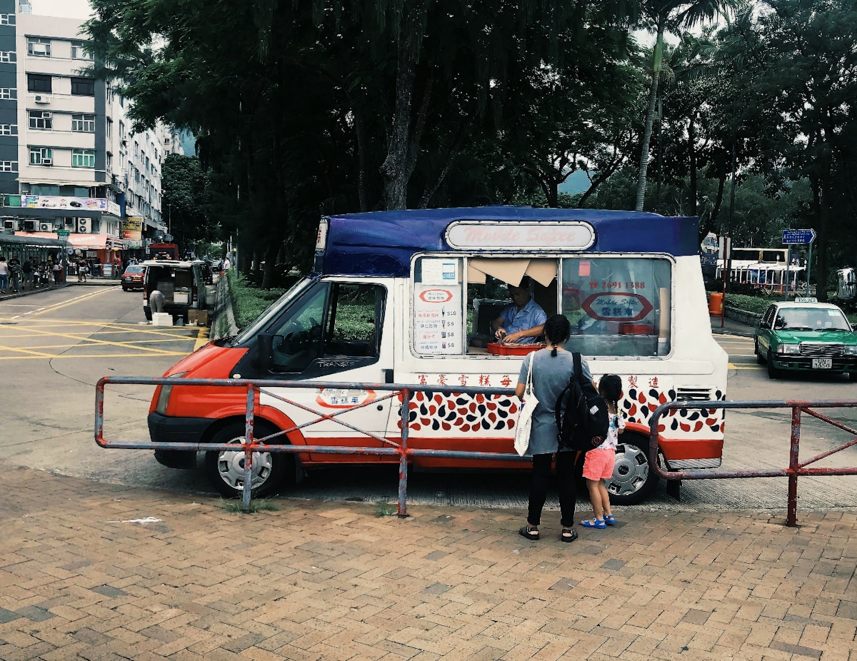 Camion-restaurant coloré avec deux clients dans une rue animée.