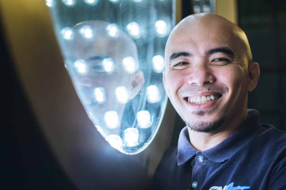 Homme souriant avec un visage éclairé par des lumières brillantes.