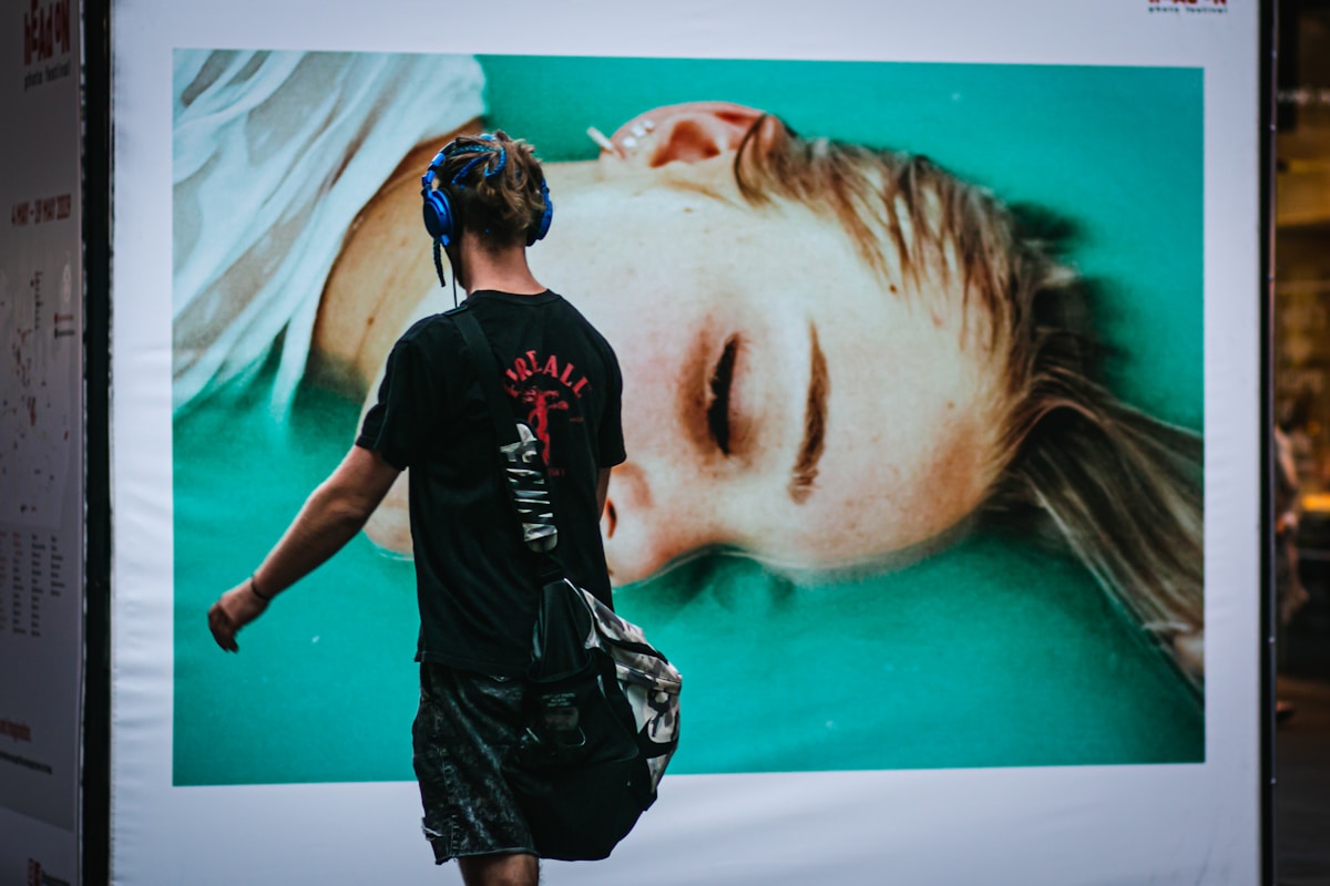 Homme de dos devant une grande affiche d'un visage féminin.