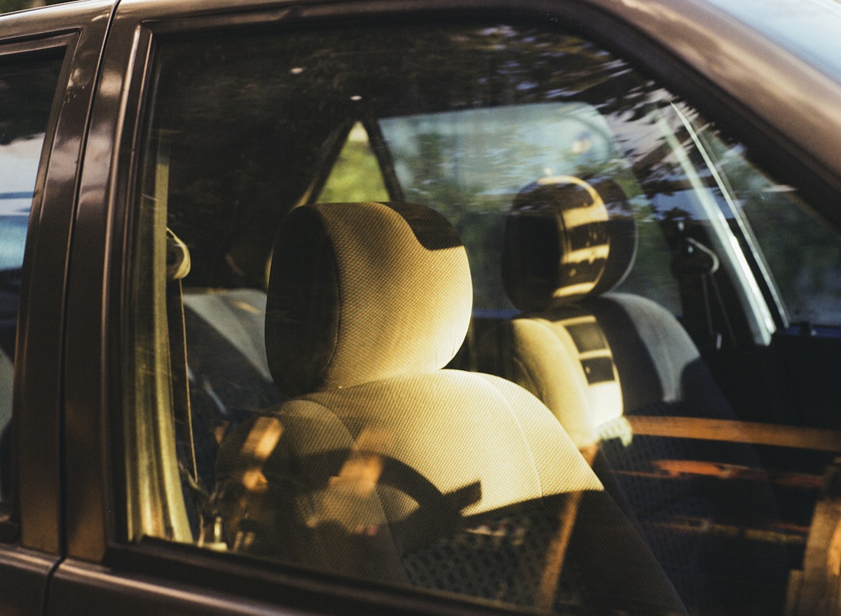 Intérieur de voiture avec sièges beiges et reflet du paysage.