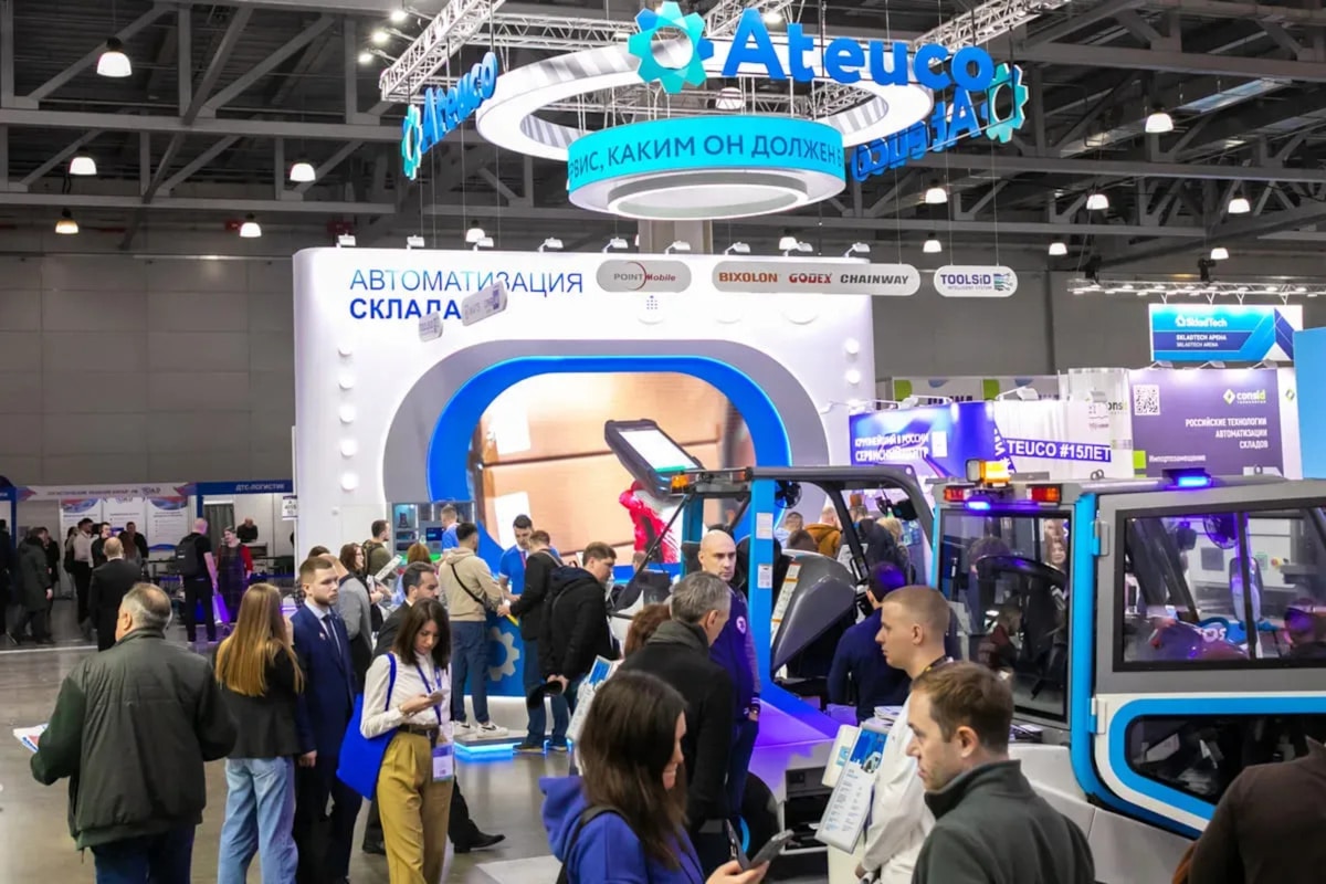 Salon commercial avec stands d'exposition, équipements de manutention et foule de visiteurs.