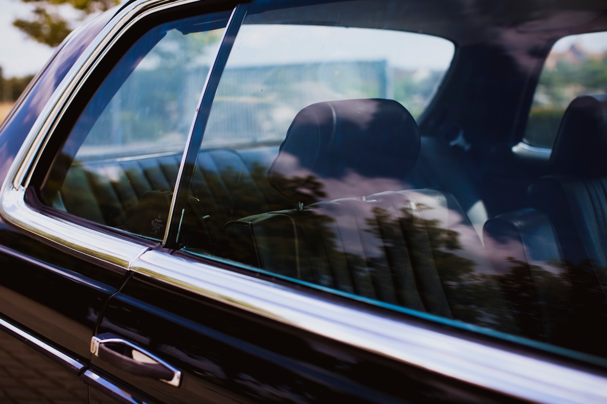 Voiture noire avec reflet de paysage dans la vitre.