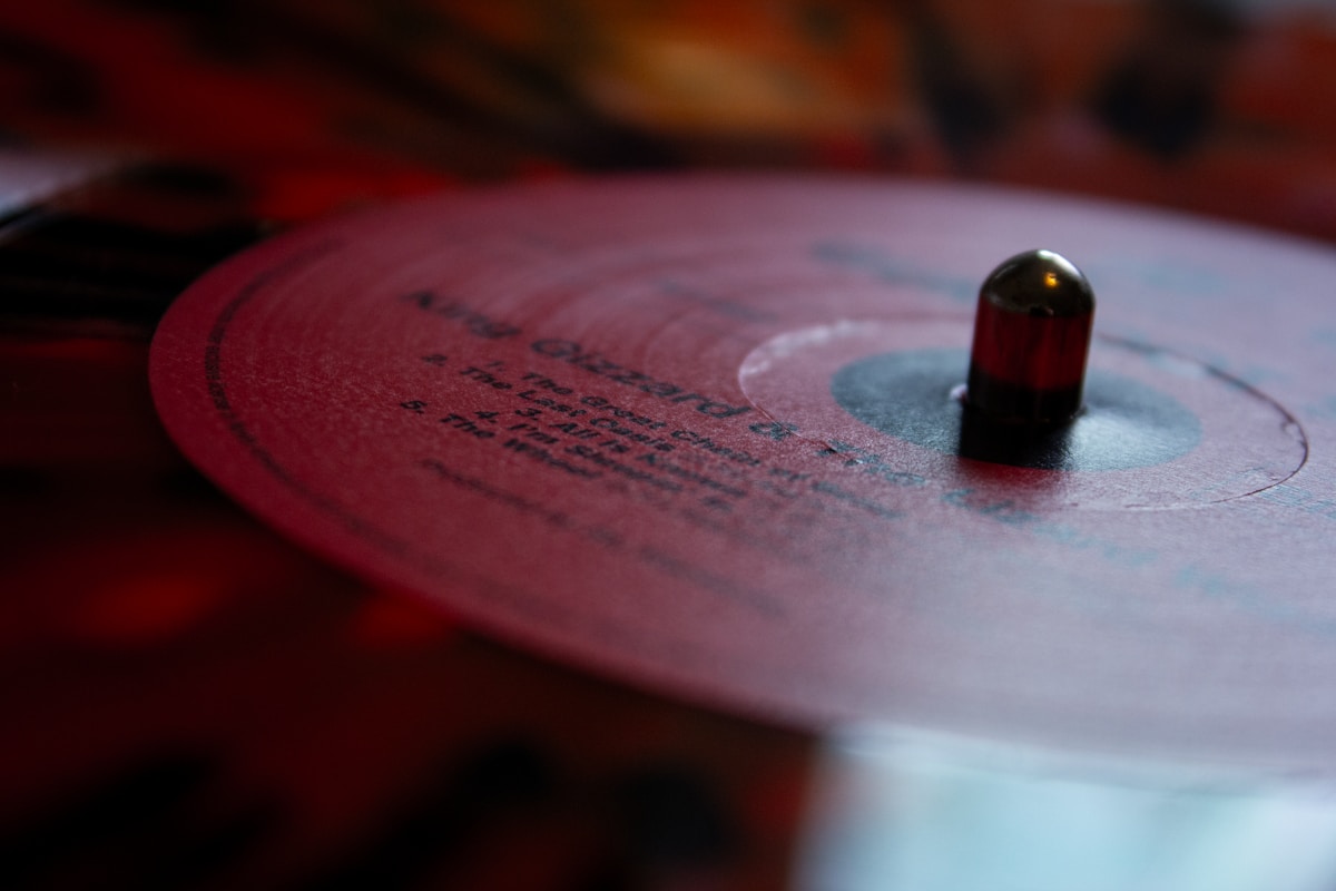 Disque vinyle rouge avec texte manuscrit et capsule noire.