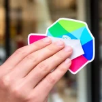 Choisir autocollants vitrine impactants pour votre commerce, main tenant un autocollant vinyle coloré pour une vitrine attray