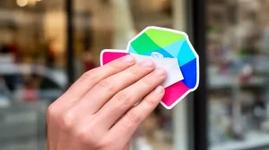 Choisir autocollants vitrine impactants pour votre commerce, main tenant un autocollant vinyle coloré pour une vitrine attray