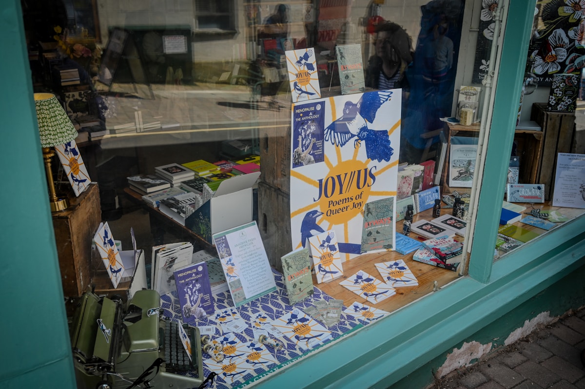 Vitrine colorée d'une librairie avec des livres et affiches sur la joie queer.