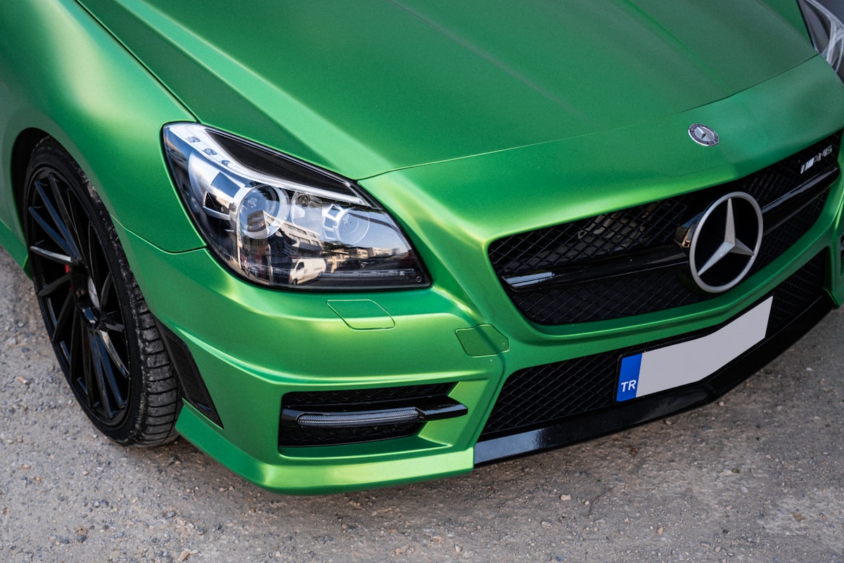 Voiture Mercedes-Benz verte métallisée avec calandre noire et jantes noires.