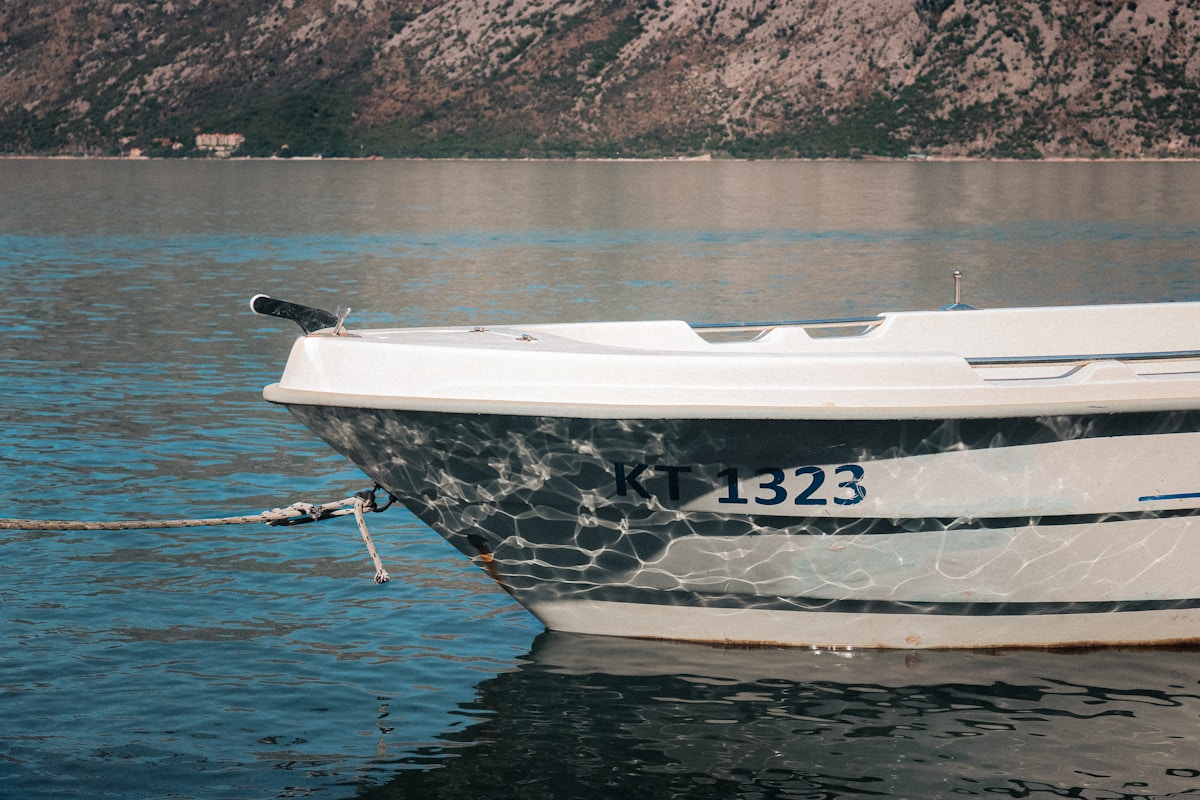 Bateau blanc et gris sur un lac bleu entouré de montagnes.