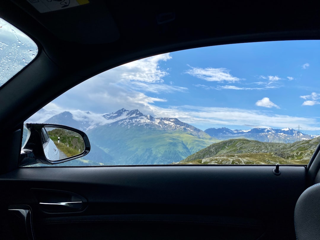 "Nuages blancs sur des montagnes enneigées, avantages des films teintés voiture en Suisse pour une conduite confortable."
