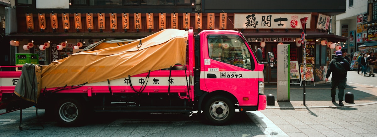 Camion de livraison rouge vif dans une rue animée de Tokyo.