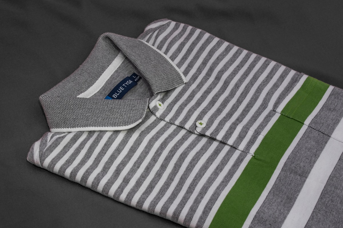 Chemise rayée grise et blanche avec détails verts.