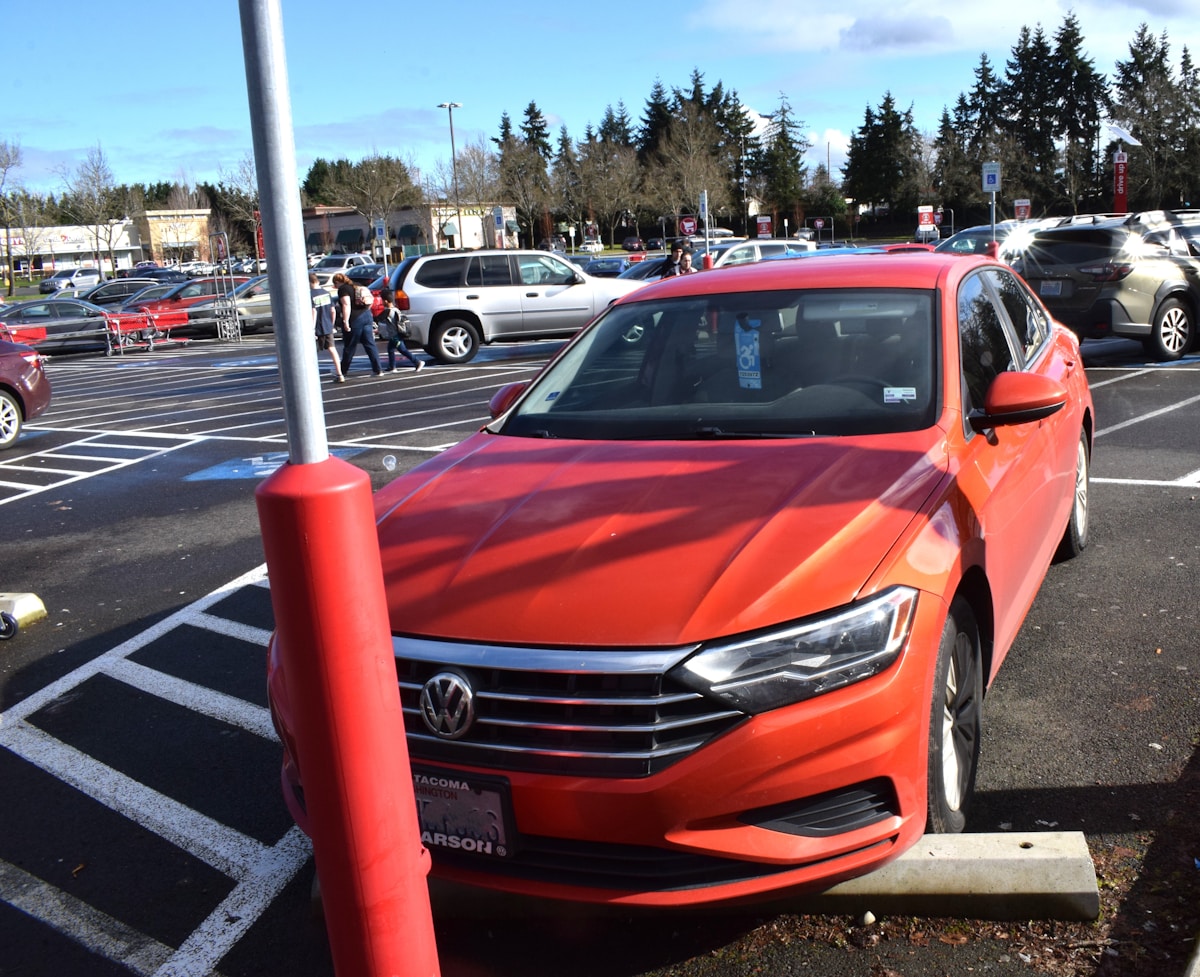 Voiture Volkswagen Jetta rouge vif dans un parking.