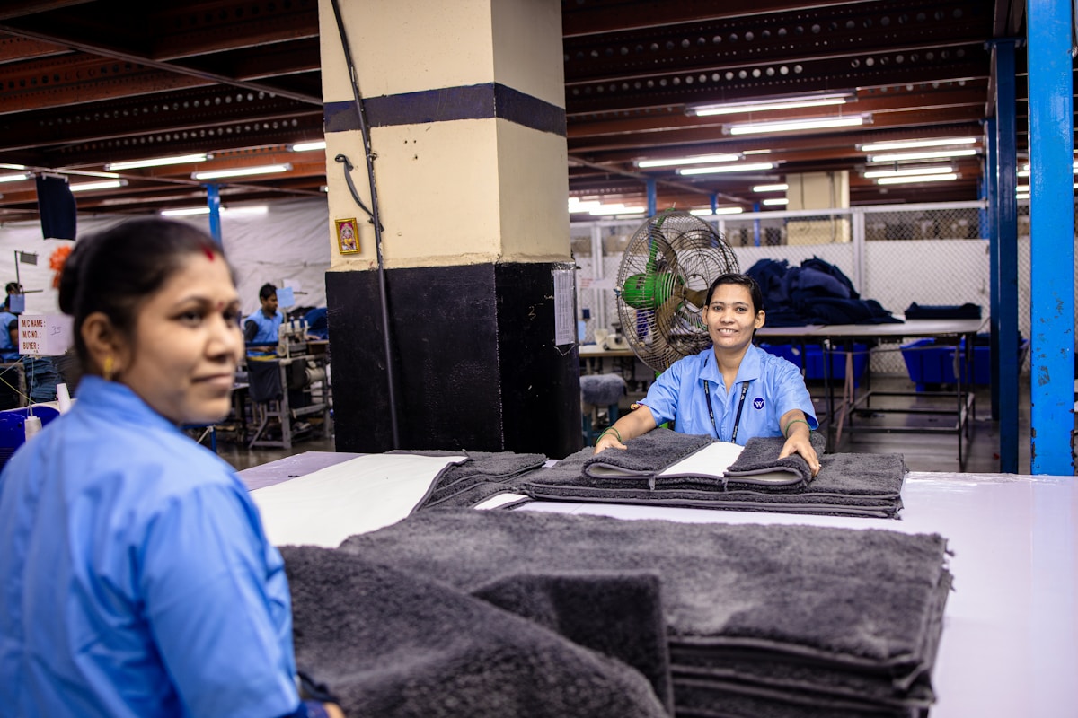 Deux employées dans un entrepôt, pliant et empilant des vêtements.