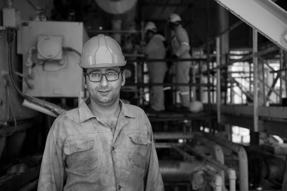 Homme souriant en casque de sécurité dans un atelier industriel.