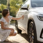 SUV blanc sous protection anti‑UV en plein jardin suisse, maman appliquant le spray.