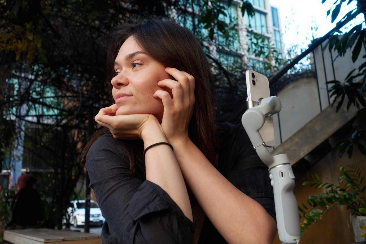 Femme pensive au téléphone dans un environnement urbain verdoyant.