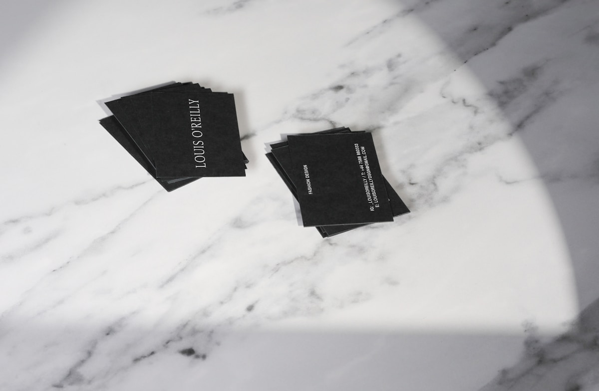 Cartes de visite noires sur fond de marbre blanc.