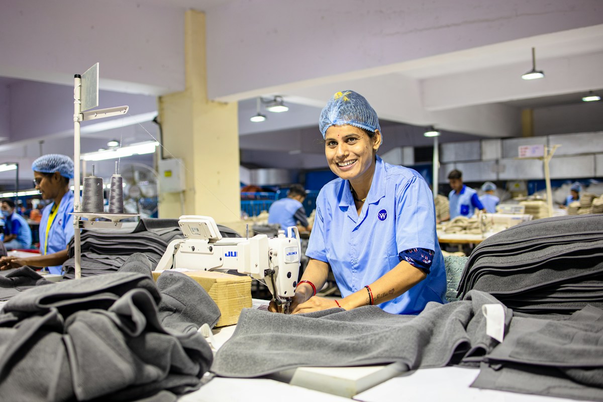 Ouvrière souriante cousant des vêtements dans une usine textile