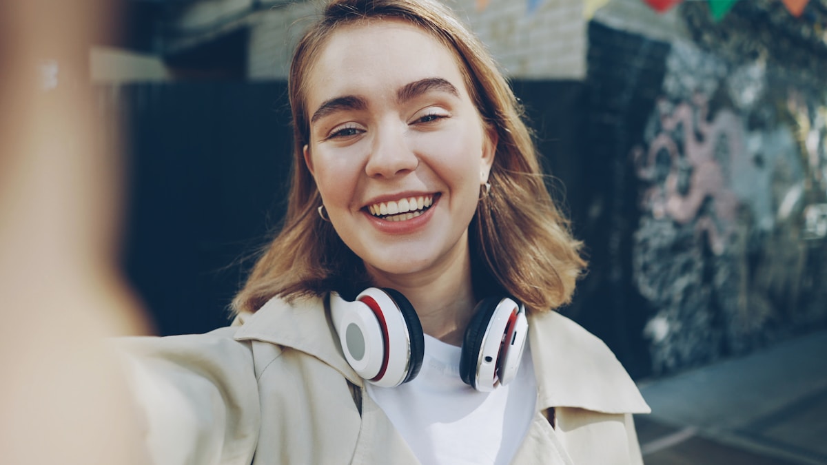 Jeune femme souriante portant des écouteurs blancs.