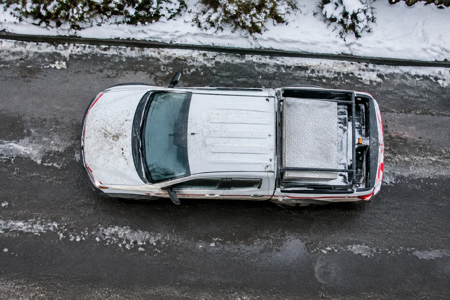 Vue aérienne d’un véhicule utilitaire blanc enneigé sur route verglacée